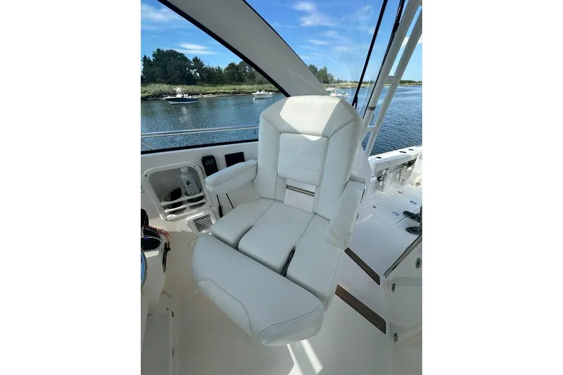 Slide: The Image of Captain's chair on 2022 Pursuit OS 325 Offshore boat, overlooking serene waterway. - 18