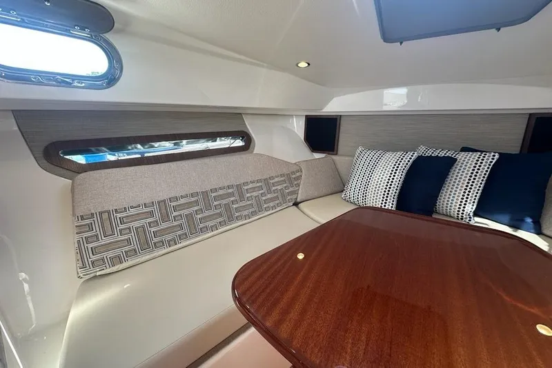 Slide: The Image of 2022 Pursuit OS 325 Offshore cabin interior with cushioned seating and wooden table. - 23