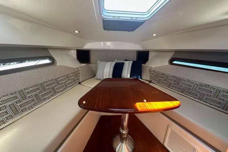 Slide: The Image of 2022 Pursuit OS 325 Offshore cabin interior with elegant seating and wooden table. - 22