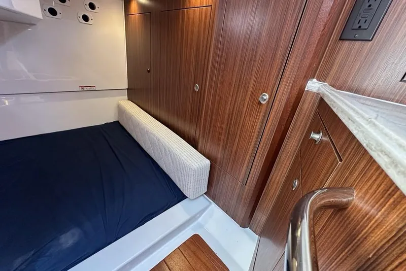 Slide: The Image of 2022 Pursuit OS 325 Offshore cabin interior with wood paneling and bed. - 28