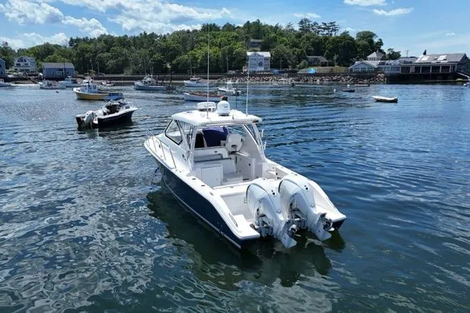 Slide: The Image of 2022 Pursuit OS 325 Offshore boat on calm water near a scenic shoreline. - 7