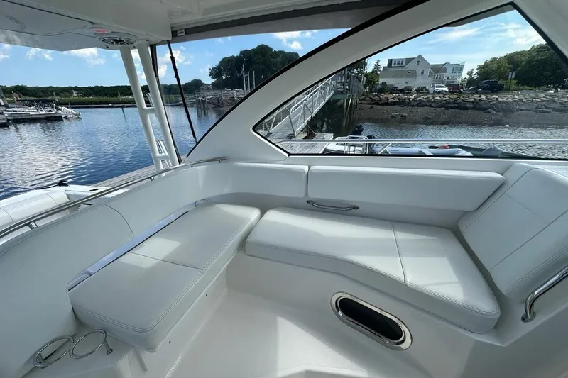 Slide: The Image of Interior view of 2022 Pursuit OS 325 Offshore boat with white seating and waterfront backdrop. - 11