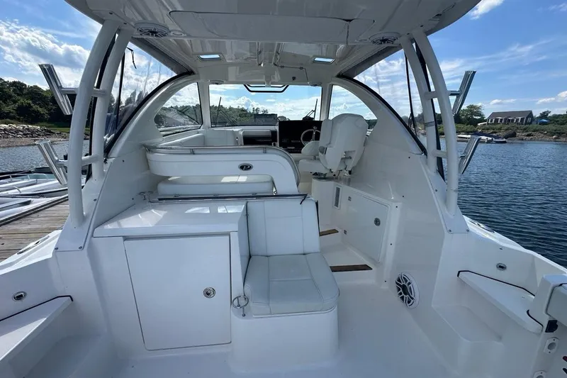 Slide: The Image of 2022 Pursuit OS 325 Offshore boat interior with seating and helm, docked by the water. - 10