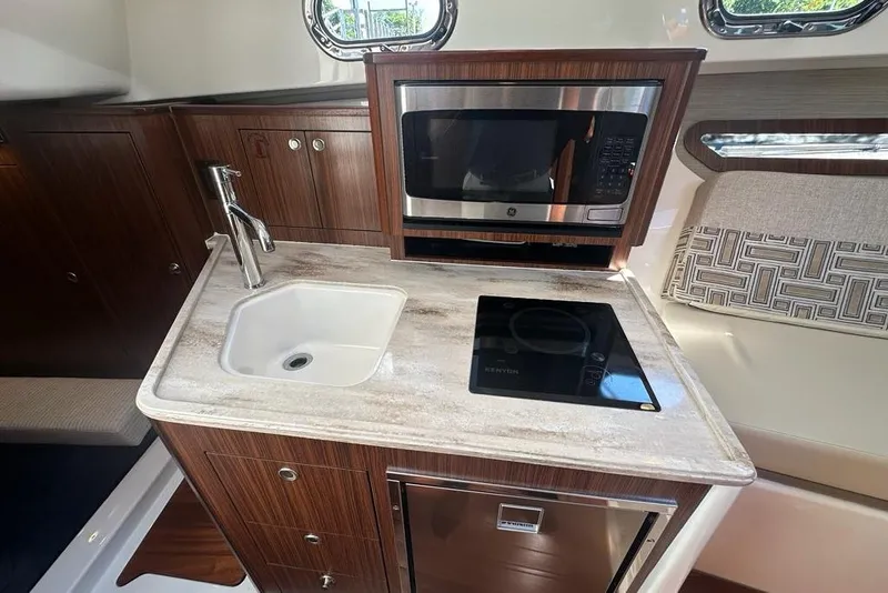 Slide: The Image of 2022 Pursuit OS 325 Offshore yacht kitchen with sink, microwave, and stovetop. - 30