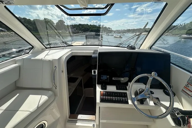 Slide: The Image of 2022 Pursuit OS 325 Offshore boat interior with steering wheel and navigation controls. - 12