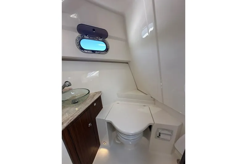 Slide: The Image of 2022 Pursuit OS 325 Offshore boat bathroom with modern fixtures and porthole window. - 33