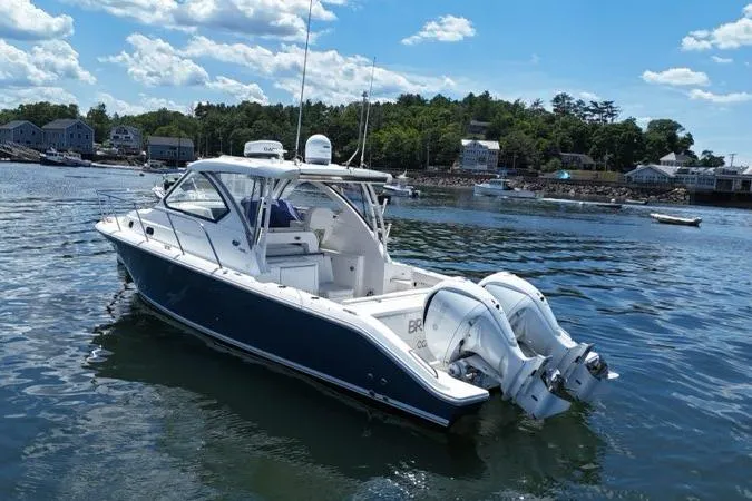 Slide: The Image of 2022 Pursuit OS 325 Offshore boat on calm water, with scenic shoreline background. - 6