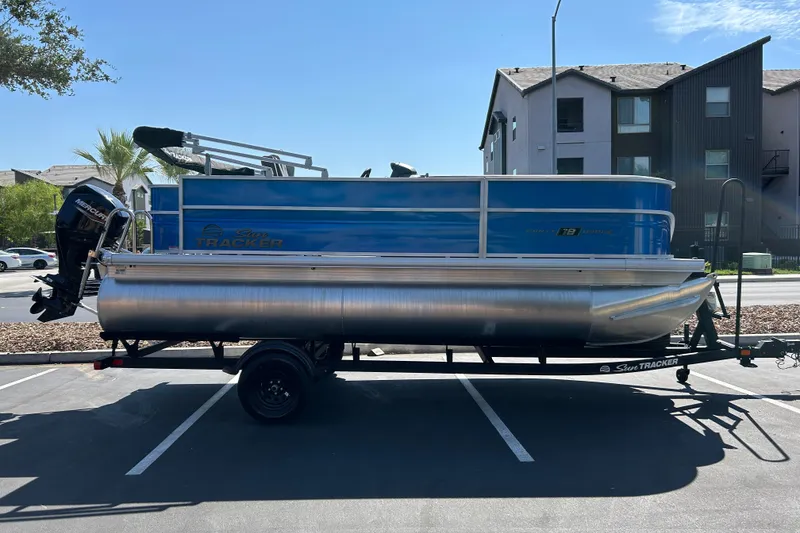 The Image of 2026 Sun Tracker Party Barge 18 DLX pontoon boat on trailer in parking lot. - 0