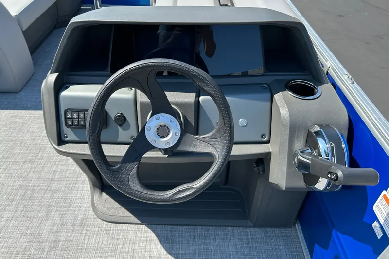 Slide: The Image of 2026 Sun Tracker Party Barge 18 DLX steering console with controls and cup holder. - 21