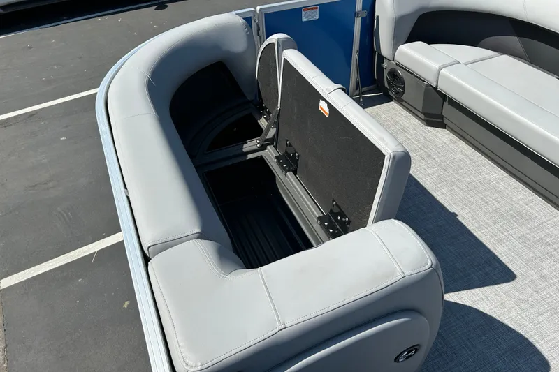 Slide: The Image of 2026 Sun Tracker Party Barge 18 DLX interior with open storage compartment and gray seating. - 15