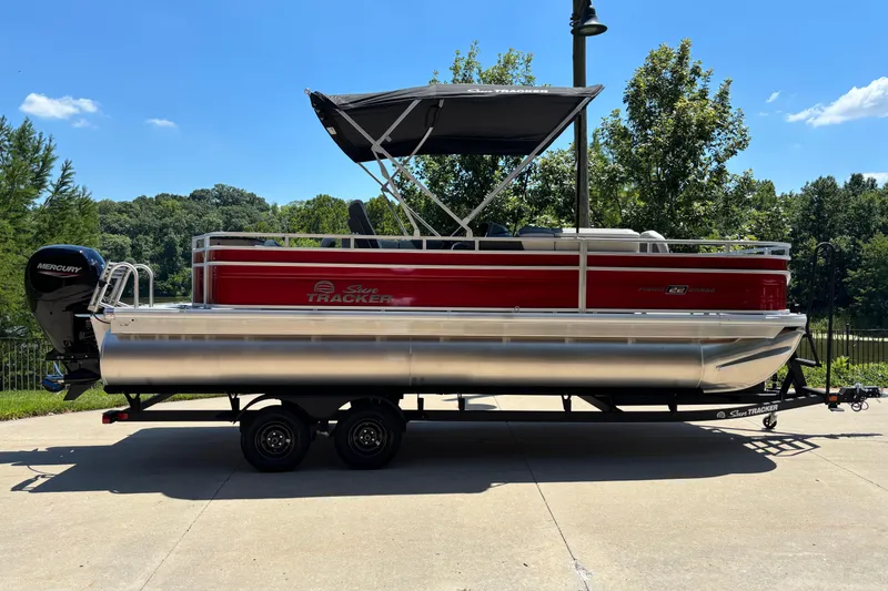 The Image of 2026 Sun Tracker Fishin' Barge 22 DLX pontoon boat on trailer, parked outdoors. - 0