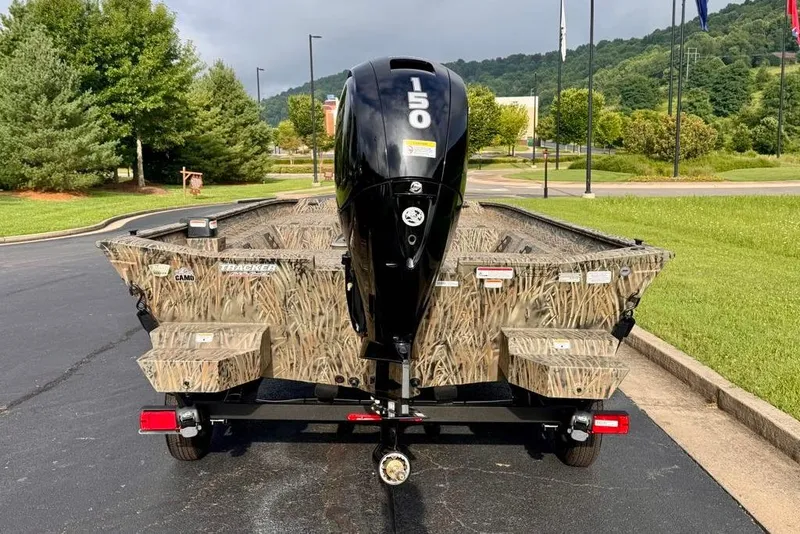 Slide: The Image of 2026 Tracker Grizzly 2072 CC boat with camo design and 150 HP engine, parked outdoors. - 5