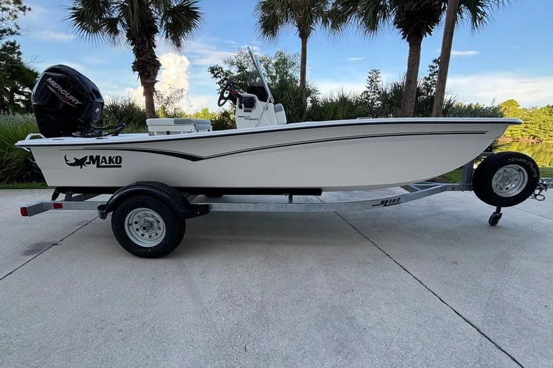 The Image of 2026 Mako Pro Skiff 15 CC boat on trailer, parked outdoors near palm trees. - 0