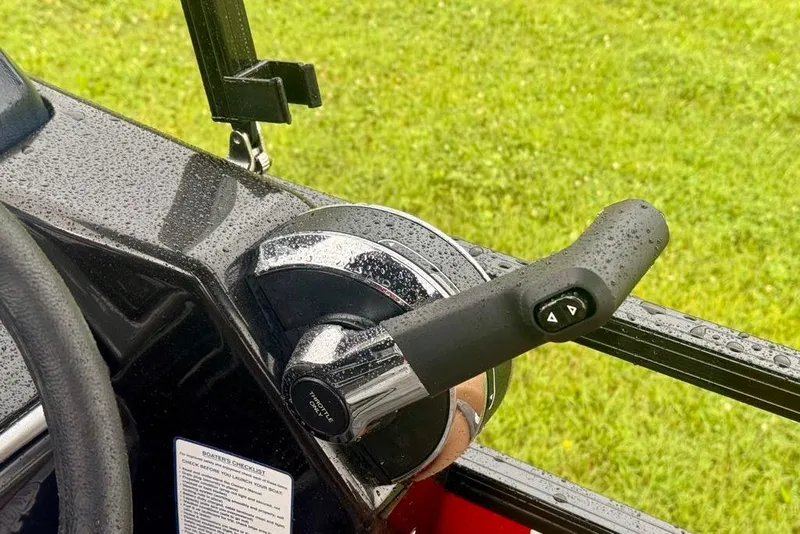 Slide: The Image of Throttle control of 2026 Ranger 223FC boat, wet with rain, on grassy background. - 8