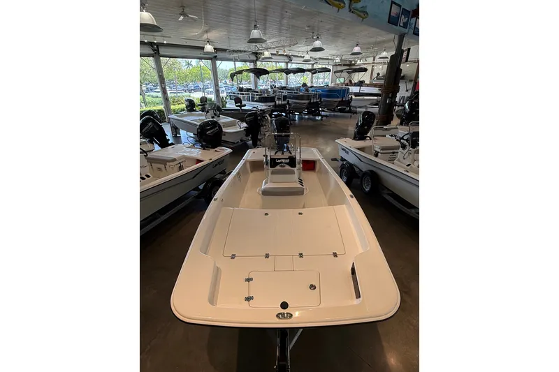 Slide: The Image of 2026 Mako Pro Skiff 17 CC boat displayed in a showroom with other boats. - 6