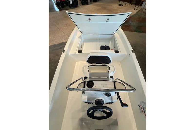 Slide: The Image of 2026 Mako Pro Skiff 17 CC boat interior with open storage compartment and steering console. - 7