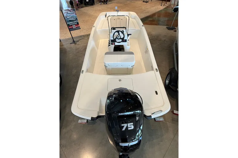 Slide: The Image of 2026 Mako Pro Skiff 17 CC boat with Mercury 75 engine displayed indoors. - 5
