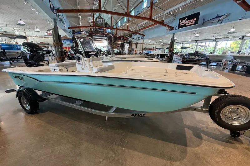 Slide: The Image of 2026 Mako Pro Skiff 17 CC boat displayed in a showroom on a trailer. - 2