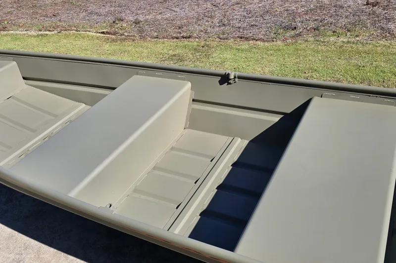 Slide: The Image of 2026 Tracker Grizzly 12 Jon boat interior with bench seats, shown outdoors. - 2