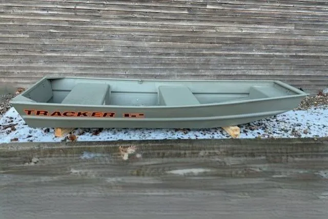 The Image of 2026 Tracker Grizzly 12 Jon boat, green, displayed outdoors on wooden supports. - 0