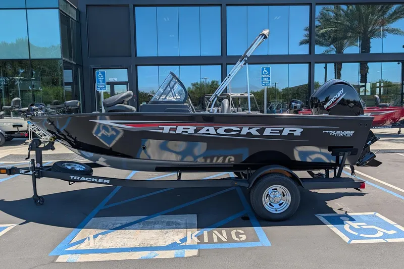 Slide: The Image of 2026 Tracker Pro Guide V-175 Combo boat on trailer, parked in front of a building. - 2