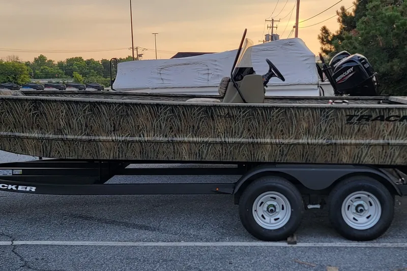 The Image of 2026 Tracker Grizzly 2072 CC boat on trailer, camo design, parked outdoors. - 0