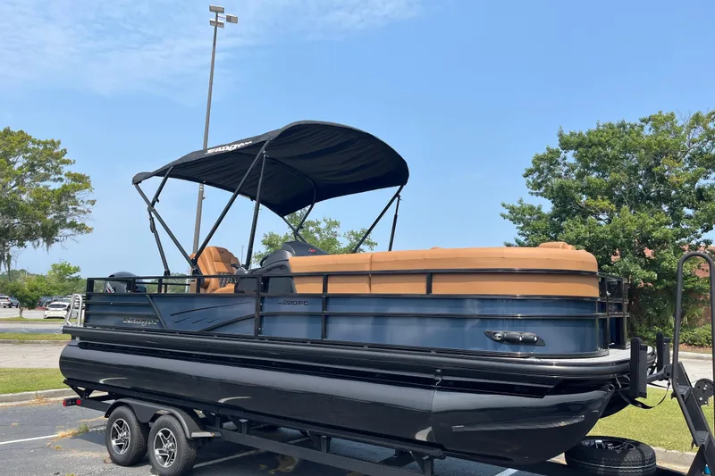 The Image of 2026 Ranger 220FC pontoon boat with canopy on trailer, parked outdoors. - 0