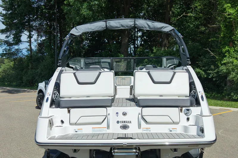Slide: The Image of 2023 Yamaha Boats 252S rear view, showcasing sleek design and seating, parked outdoors. - 11