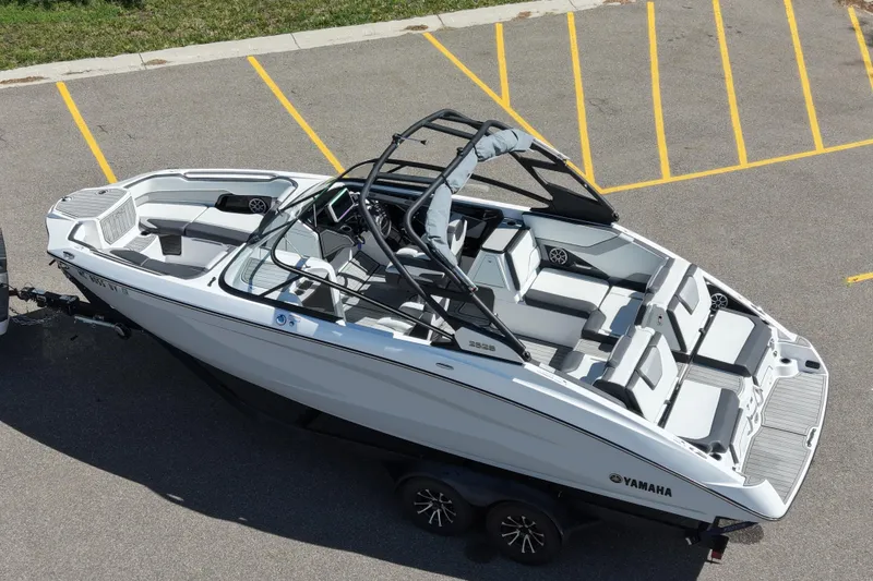 Slide: The Image of 2023 Yamaha Boats 252S on trailer, sleek design, spacious seating, parked in lot. - 12