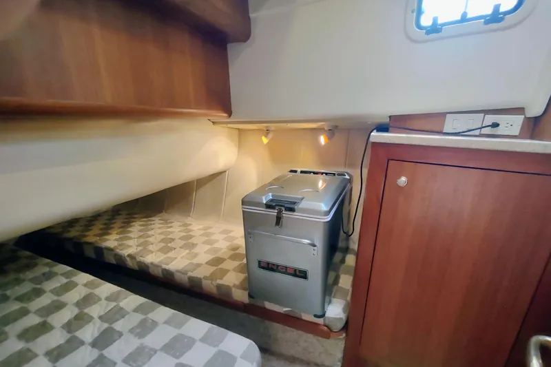 Slide: The Image of Cozy cabin interior of 2000 Mainship 390 Trawler with compact fridge and wooden cabinetry. - 76