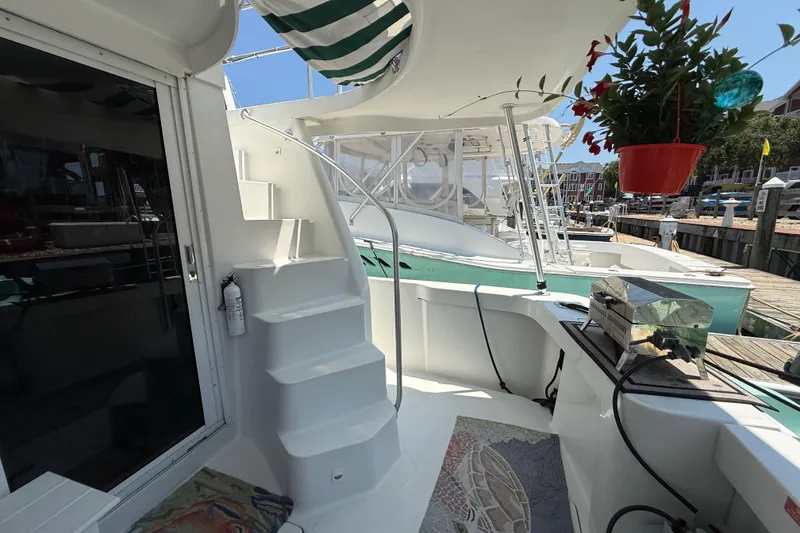 Slide: The Image of 2000 Mainship 390 Trawler deck with stairs, grill, and potted plant at marina. - 11