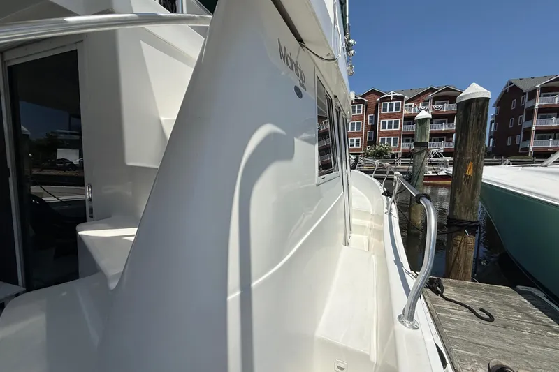 Slide: The Image of 2000 Mainship 390 Trawler docked at marina, showcasing sleek white exterior and railing. - 14
