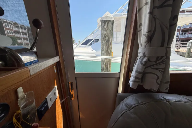 Slide: The Image of Interior view of a 2000 Mainship 390 Trawler, showing a docked boat through the window. - 61