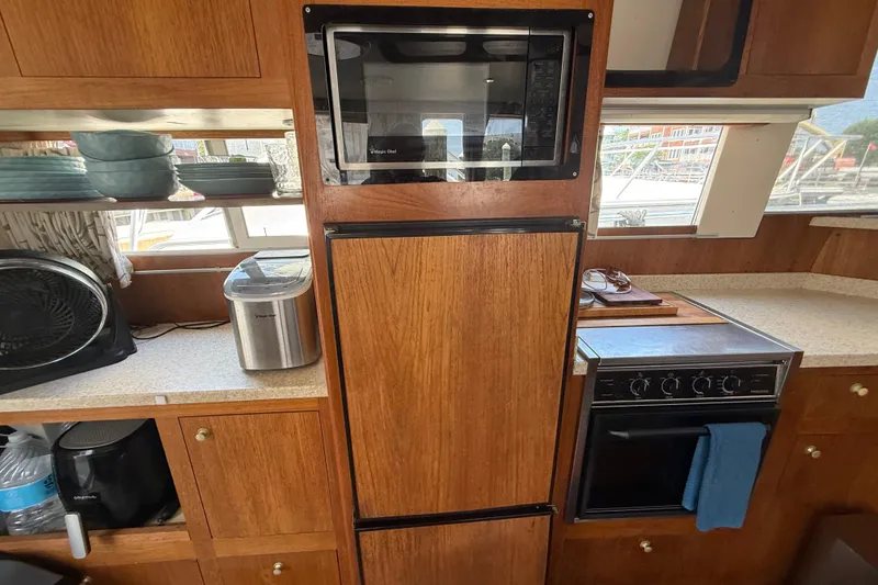Slide: The Image of Kitchen area of a 2000 Mainship 390 Trawler with wooden cabinetry and modern appliances. - 65