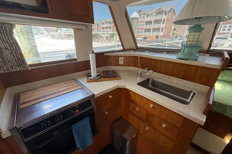 Slide: The Image of Interior of 2000 Mainship 390 Trawler featuring kitchen with stove, sink, and wooden cabinetry. - 64