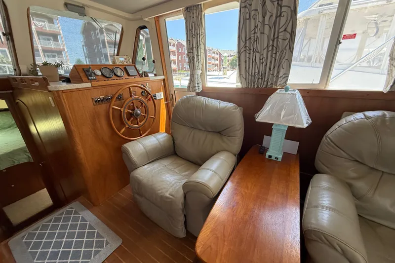 Slide: The Image of Interior of 2000 Mainship 390 Trawler with leather chairs, wooden helm, and nautical decor. - 56