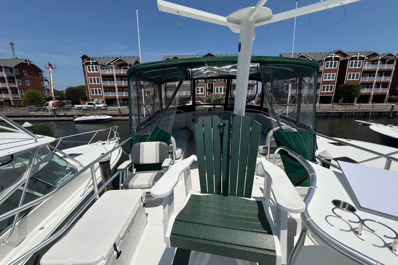 Slide: The Image of 2000 Mainship 390 Trawler docked, featuring green seating and covered helm, with waterfront buildings. - 34
