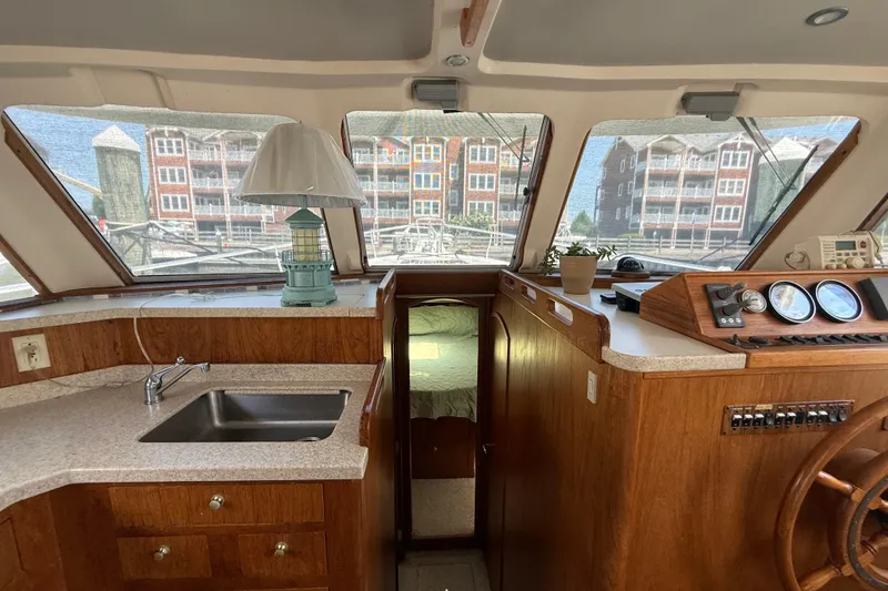 Slide: The Image of Interior of 2000 Mainship 390 Trawler with helm, sink, and wooden cabinetry. - 54