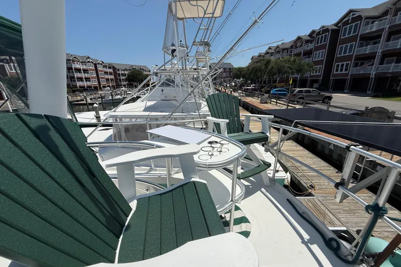 Slide: The Image of 2000 Mainship 390 Trawler docked, featuring green chairs and a table on deck. - 29
