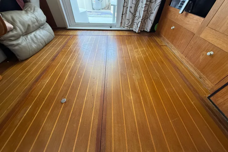 Slide: The Image of Wooden interior flooring of a 2000 Mainship 390 Trawler, featuring polished finish and cabinetry. - 78