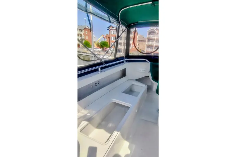 Slide: The Image of 2000 Mainship 390 Trawler interior with seating and windows, docked near waterfront buildings. - 27