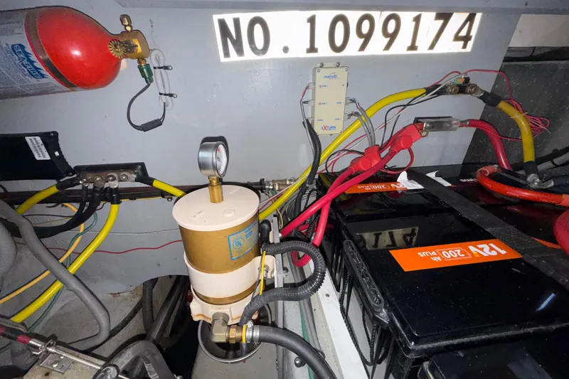 Slide: The Image of Engine room of 2000 Mainship 390 Trawler with wiring, battery, and fire extinguisher. - 86