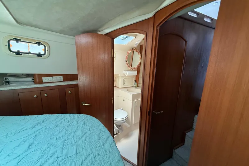 Slide: The Image of Interior of 2000 Mainship 390 Trawler showing bedroom and bathroom with wooden cabinetry. - 71
