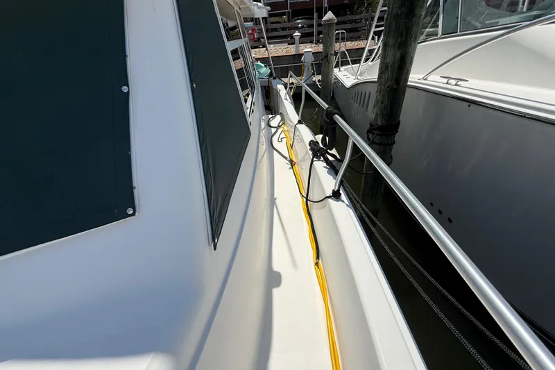 Slide: The Image of 2000 Mainship 390 Trawler docked, showing side deck and railing details. - 53
