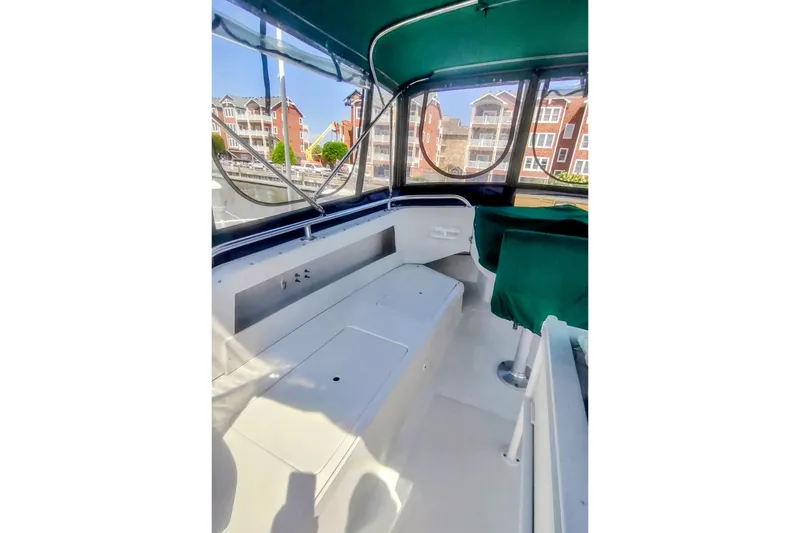 Slide: The Image of Interior view of 2000 Mainship 390 Trawler with green seating and marina backdrop. - 26