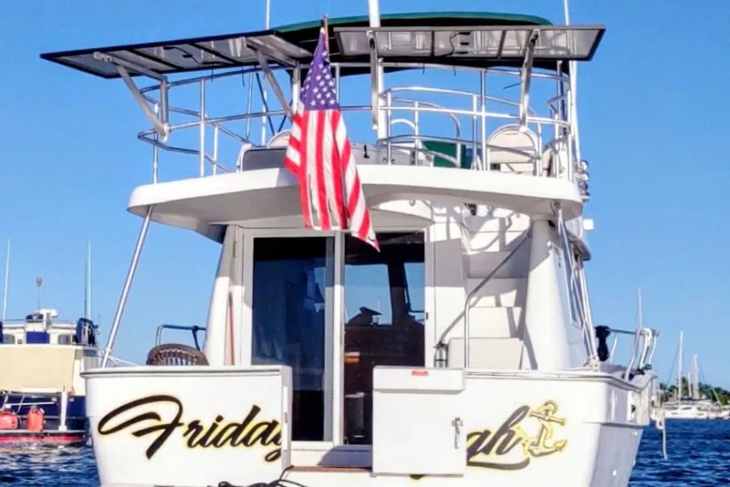 Slide: The Image of Mainship 390 Trawler 2000 with American flag, docked on a sunny day. - 1
