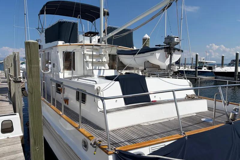 Slide: The Image of 2001 Grand Banks 42 Classic yacht docked at marina, featuring upper deck and dinghy. - 3
