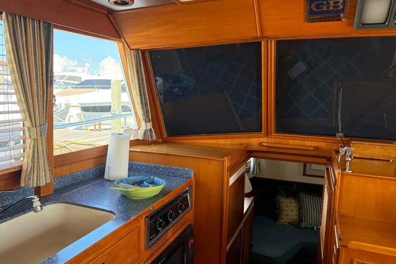 Slide: The Image of Interior of 2001 Grand Banks 42 Classic yacht, featuring a cozy kitchen area with wood finish. - 8
