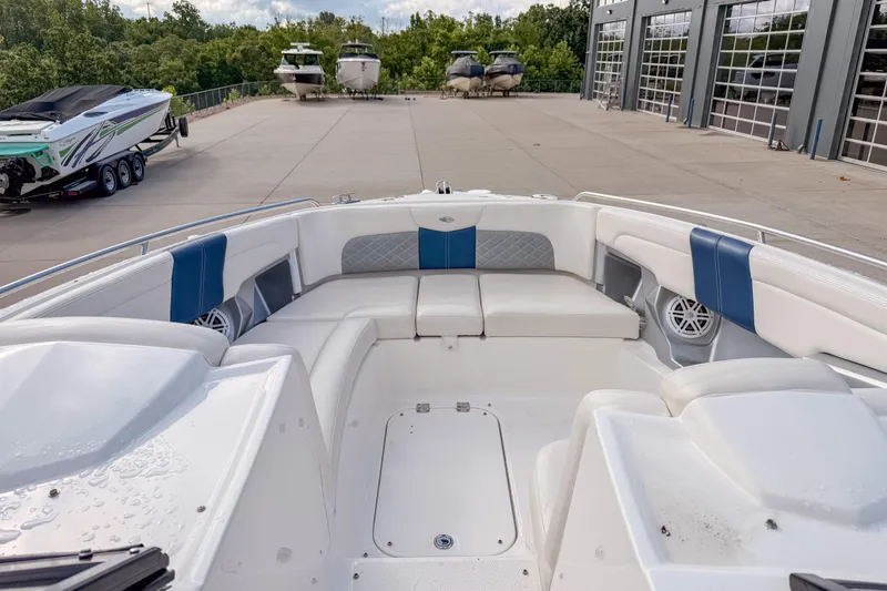 Slide: The Image of 2012 Chaparral 327 SSX boat interior with white and blue seating, docked near other boats. - 17
