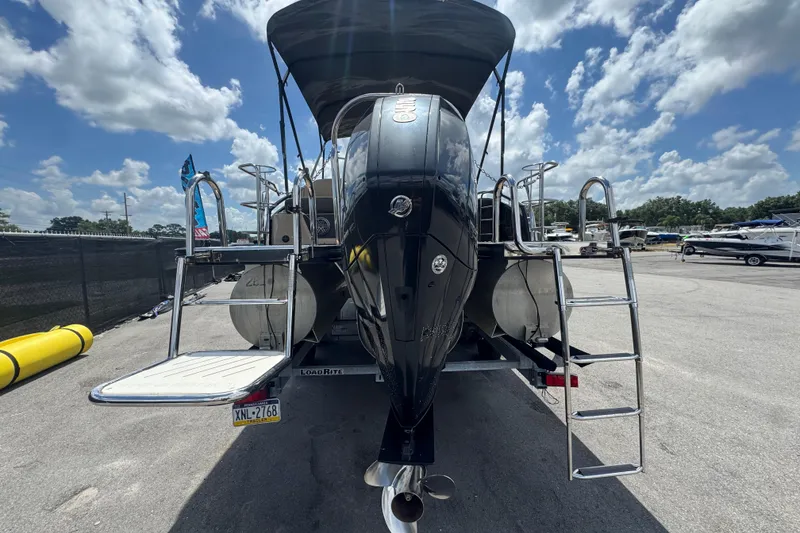 Slide: The Image of 2021 Harris Solstice 230 pontoon boat with dual ladders and trailer, under a sunny sky. - 67